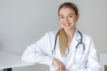 Smiling doctor in a white coat with a stethoscope in a modern office