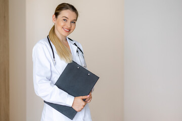 Smiling medical professional holding a clipboard in a modern office
