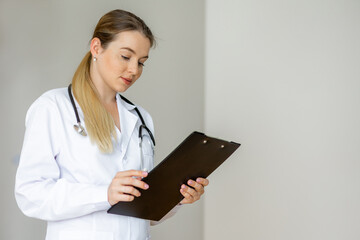 Professional female doctor reviewing clipboard in a clinical setting