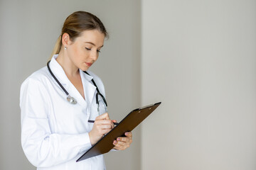 Female doctor writing notes on a clipboard during a clinical examination