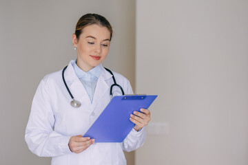 Professional doctor reviewing patient records on clipboard in medical office