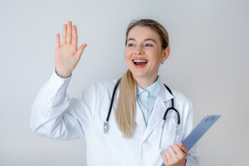 Smiling female doctor welcoming patients with clipboard and stethoscope in office