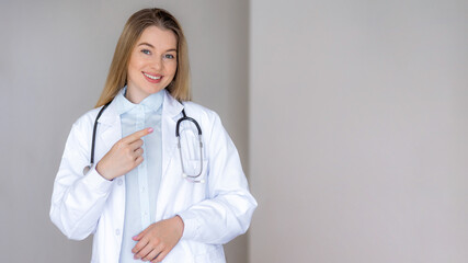 Smiling medical professional with stethoscope promoting healthcare in a studio setting point finger at copy space