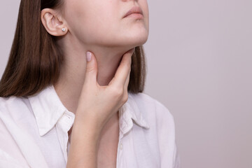 Close-up of woman touching her neck suffering from throat pain, painful swallowing. Symptoms of...