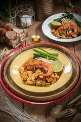 Pad Thai Pad Thai with rice vermicelli and shrimp with ingredients placed on the table.