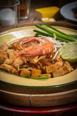 Pad Thai Pad Thai with rice vermicelli and shrimp with ingredients placed on the table.
