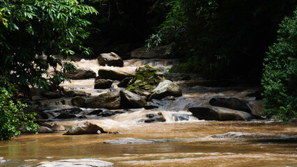 The nature of the waterfall in the forest that flows strongly during the rainy season. Strong current in the river, waters turned muddy after heavy rains in autumn.