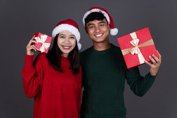 Portrait of Happy Young Asian Man and Woman Hold Present Box Wearing Santa Hat, Christmas Holiday Concept