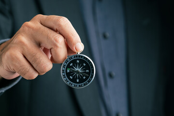 Close-up of businessman showing a compass toward the camera, symbolizing vision, leadership,...