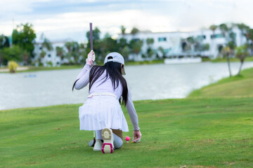 Asian woman happy and fun while playing golf on the golf course. Golfer hitting golf shot with...
