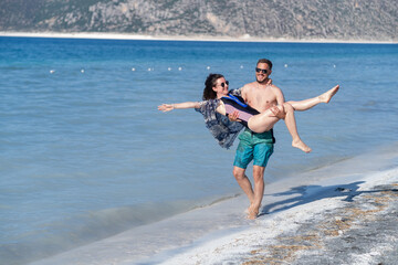 Couple Enjoying a Playful Moment at a Beach in a Sunny Tropical Paradise While Wading Through...