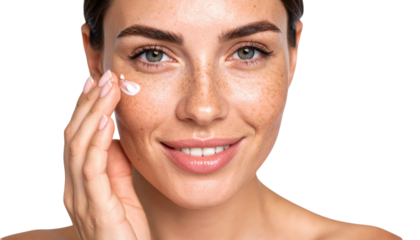 A smiling woman with clear skin applies cream to her cheek, showcasing a skincare routine and natural beauty.