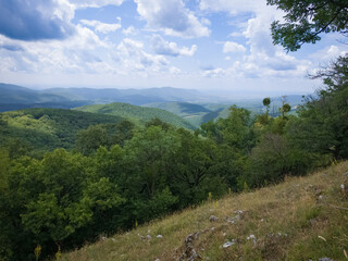 Wide-angle photo from Sima-kő capturing sunlit forested ridges and the undulating terrain of the...