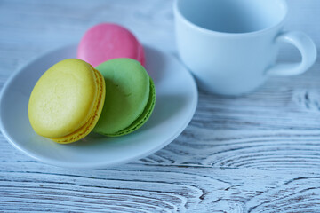 Colorful macaroons on a white plate with a cup of coffee