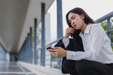 Stressed businesswoman reading bad news on smartphone in office building corridor