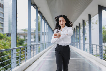 Businesswoman running late checking time on smartwatch in modern city