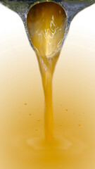Orange juice from a juicer is flowing onto an orange background.