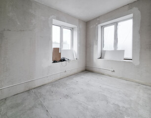 House interior renovation or construction unfinished. Empty room with two big windows and white...