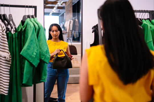 Woman shopping and trying on outfit in clothing store with mirror