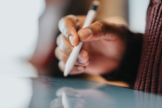 Fototapeta Detailed view of a person interacting with a digital touch screen, showcasing their hand holding a stylus for precision input in design, note-taking, or creative tasks.