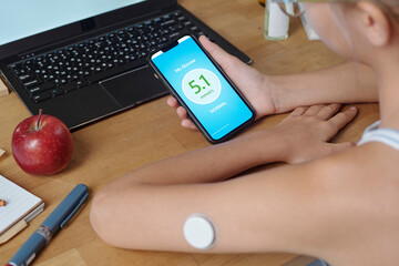 Person at home monitoring glucose level with insulin patch and app