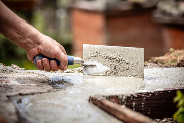 man smoothes fresh concrete in the foundation with a trowel