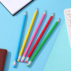 Pencils of various colors placed on a blue paper, children's learning stationery