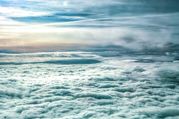 Aerial view above dense layer of fluffy white cumulus clouds stretching to horizon under vast sky