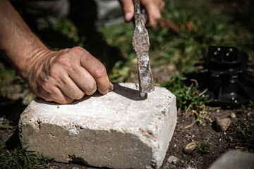 a man drills holes for plugs in concrete or brick