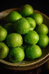 Green plums on dark tone photography background with shiny water drops