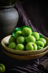 Green plums on dark tone photography background with shiny water drops