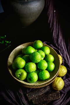 Green plums on dark tone photography background with shiny water drops
