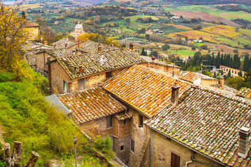Tuscany panoramic landscape with old traditional houses roofs, cypress, vineyards, Italy