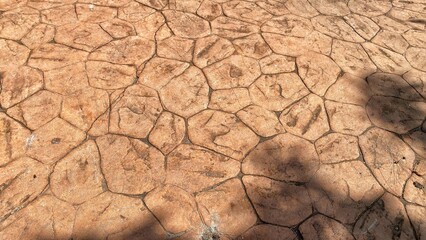 Close-up of a decorative floor made from simulated large tiles or stamped concrete, showcasing variations in color and shape, with subtle shadows.