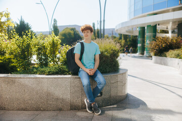 Teen boy waits outside with backpack in casual summer outfit