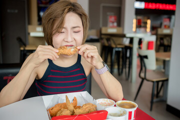 Woman is eating fried chicken intently while sitting at a restaurant