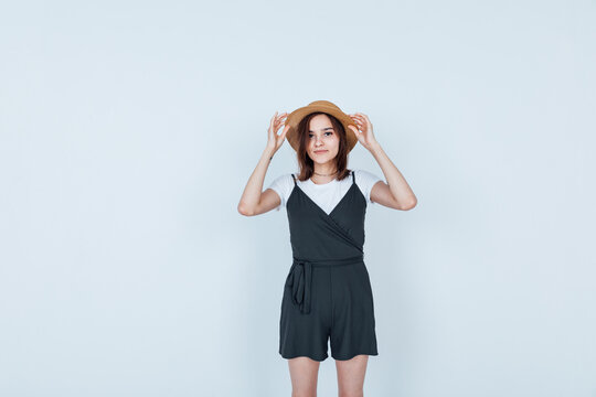 brunette woman in sherts and straw hat on white background