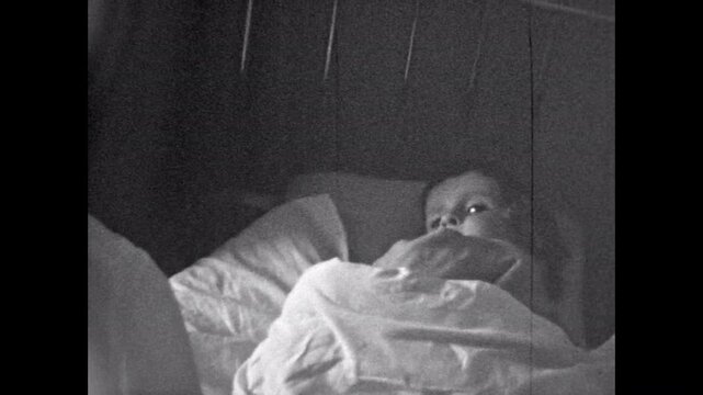 Old Film, Adorable little child lying sleep to bed. Mother putting active, restless cute girl toddler to bed in bedroom. Funny family moments. Vintage archive. Archival playful family retro 1960s