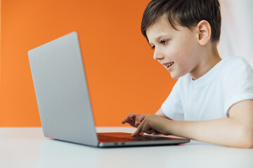 Boy working at desk with study laptop at school