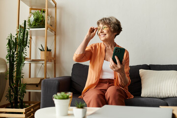 Senior woman enjoying a cozy moment at home while using her smartphone and smiling warmly