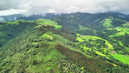 Stunning aerial shot showcasing the beautifully vibrant green hills and valleys beneath a dramatic...