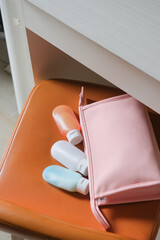 travel sized plastic containers for toiletry and pink cosmetic bag on chair in the hotel room