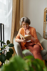 Senior woman enjoys reading a book while sitting comfortably in her cozy home environment