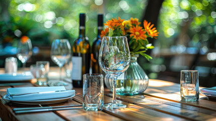 Elegantly set table with flowers, wine, and glassware, ready for a meal in a natural outdoor setting.