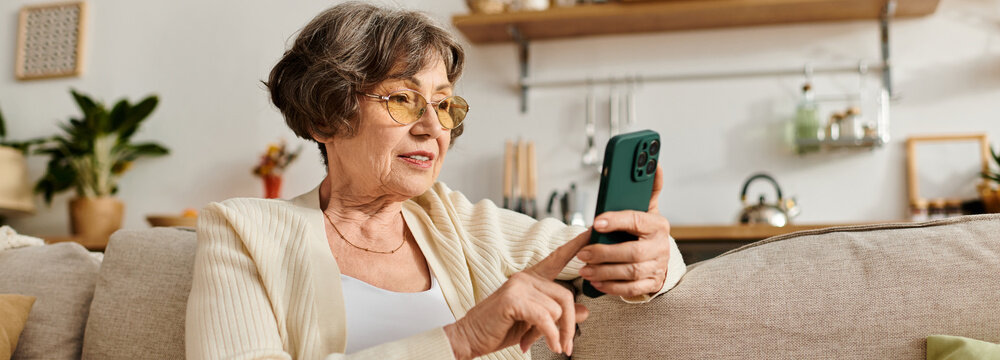Senior woman enjoys a relaxing moment at home while using her smartphone and wearing cozy attire