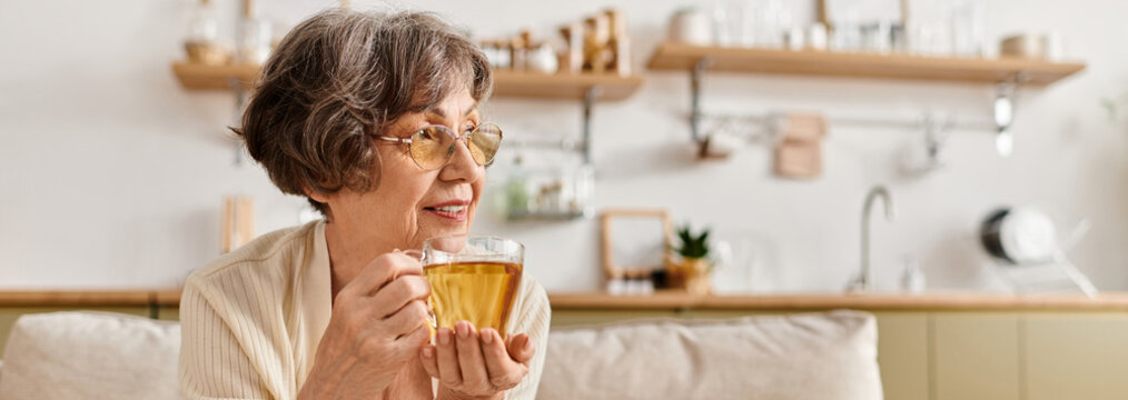 Senior woman enjoys warm drink at home in cozy attire during a relaxing afternoon moment