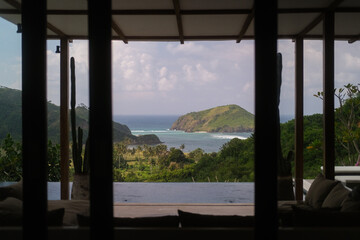 View from a luxury villa with a terrace and an infinity pool to the ocean and hills around the...