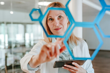 Engineer in laboratory examining molecular lattice with digital tablet