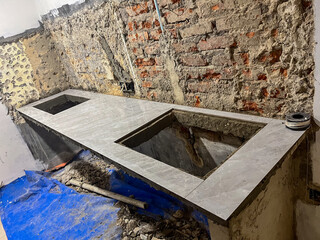 Granite kitchen countertop under construction, featuring unfinished brick walls and cutouts for...