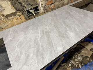 Granite kitchen countertop under construction, featuring unfinished brick walls and cutouts for sink and stove on a work-in-progress interior.